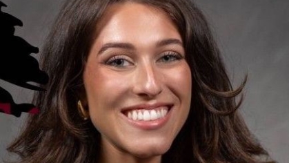 Headshot of woman with long brown hair, smiling. She is wearing a black blazer.