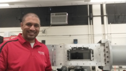man in red polo standing next to grey machine