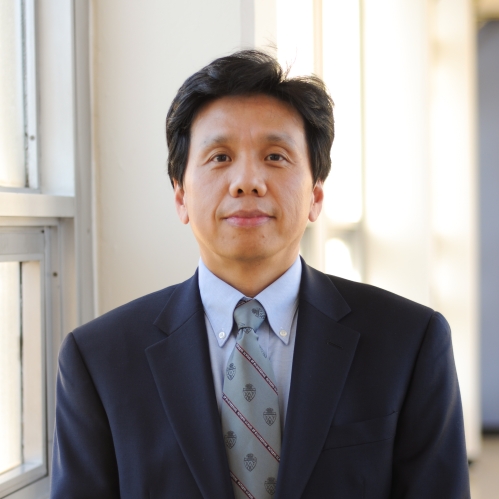 Head shot of Chinese male with short black hair, wearing a black suit, blue shirt, and patterned blue tie.