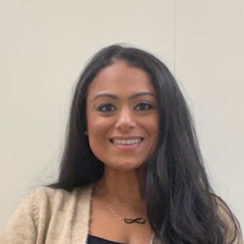 Head shot of woman with long black hair, wearing a beige sweater and a black shirt.