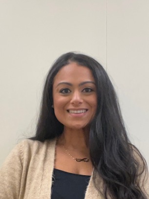 Head shot of woman with long black hair, wearing a beige sweater and a black shirt.