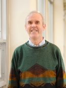 Head shot of male wearing a green pullover patterned sweater.