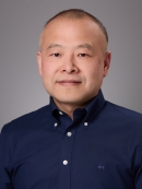 Headshot of male with dark blue button down dress shirt.