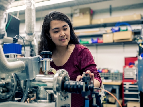 White female student works on mechanical equipment in a lab.