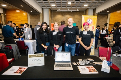 Students standing behind a table at a convention