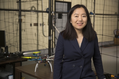 Female chinese woman in a drone lab with black hair wearing a black suit 
