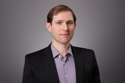 headshot of man with grey shirt and black jacket