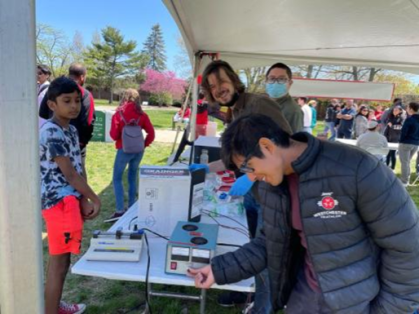 student standing around table looking at an experiment