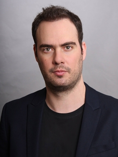 Headshot of male with short brown hair and scruffy beard.