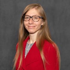 Headshot of woman with long blond hair wearing eyeglasses and a red cardigan sweater.